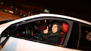 A woman drives a car and gives a thumbs up in Al Khobar, Saudi Arabia