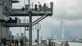 Navy crew members of the USS Blue Ridge stand on the deck as the ship is docked at a wharf during a port call on April 20, 2019 in Hong Kong