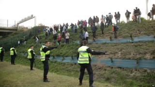 Migrants gather to attempt to overrun a police cordon by the perimeter fence of the Eurotunnel site at Coquelles in Calais, France.