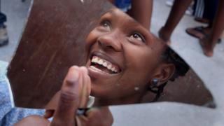 Niña sonriendo reflejada en pedazo de espejo