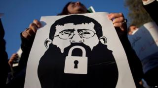 A Palestinian woman holds a poster with a drawing depicting Khader Adnan, who went on hunger strike in detention
