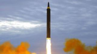 A missile is seen taking off from a grassy field in a burst of burning fuel and smoke