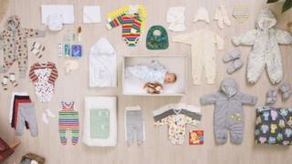 Bebê dentro da caixa de papelão, com seus produtos ao lado