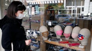 A woman wearing a face mask looks at face masks on sale in Paris