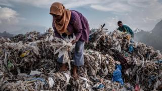 A woman collecting plastic to recycle at a import plastic waste dump in Indonesia.