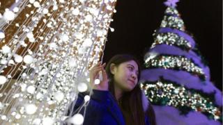 2018年12月22日,北京一名女士在圣诞树旁自拍。