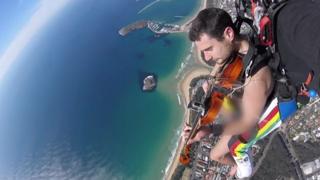 Glen Donnelly plays violin during naked skydive