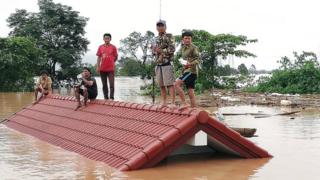 Lao villagers are stranded on a roof of a house after a dam collapsed