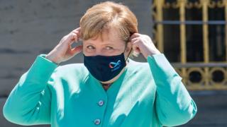German Chancellor Angela Merkel adjusts her protective mask on her way to a Bavarian state cabinet meeting at Herrenchiemsee Island, Germany, July 14, 2020