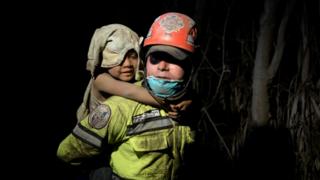 Una mujer carga a una niña