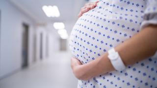 Изображение неизвестной беременной женщины в больничном халате