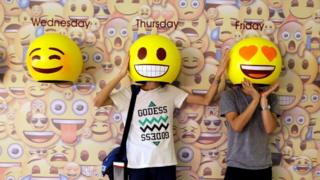 Dos personas probándose unas "máscaras" de emojis en China