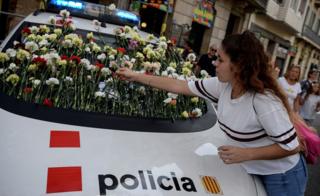 Женщина демонстрирует цветок на лобовом стекле автомобиля каталонской полиции, известного как Моссос д'Эсквадра, во время митинга за референдум в Барселоне 24 сентября 2017 года.