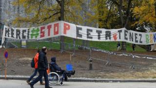 People walk past a banner hung close to the Walloon parliament in Namur on October 28, 2016