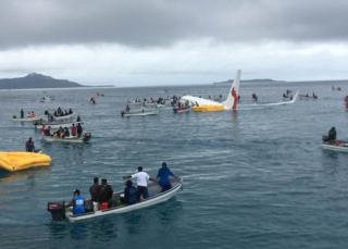 Small boats surround the Air Niugini plane in the water