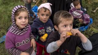Трое сирийских детей в Венгрии, один из них ест сырую кукурузу