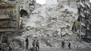 Члены гражданской обороны Сирии, известные как «Белые каски», ищут жертв среди обломков разрушенного здания после сообщений о воздушных ударах в удерживаемом повстанцами районе Катарджи в северном городе Алеппо, 17 октября 2016 года