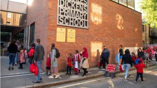 Pupils on their first day back to school at Charles Dickens Primary School, in London, queued outside with their parents at drop off time.