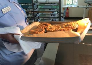 A nurse holds a tray of baked pies