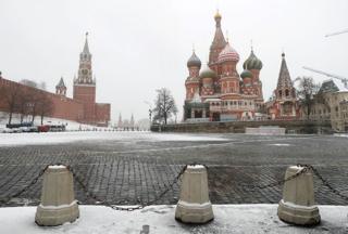 The clock on Spasskaya tower showing the time at noon, is pictured next to Moscow's Kremlin, and St. Basil's Cathedral