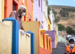 Ein Mann in einer Maske schaut auf ein Gesundheitspersonal in Bo-Kaap, Kapstadt, Südafrika - Dienstag, 7. April 2020