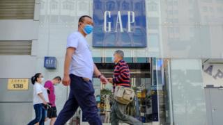 Customers walk outside a GAP store with protective masks in Beijing, China.