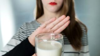 Mujer rechazando un vaso de leche.
