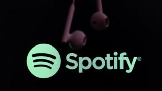A pair of headphones hangs from the top of the frame in front of the Spotify logo