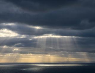 Sun rays showing through clouds over sea