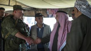 Sheikh Ahmad Mubarak, second from right, shakes hands with a Russian military officer after signing a cease-fire declaration in Maarzaf, about 15 kilometres west of Hama, Syria, Wednesday, March 2, 2016