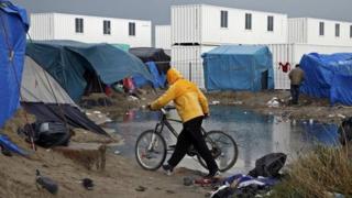 A migrant walks among tents in a makeshift camp in Calais, France. File photo