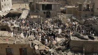 People and vendors gather on the rubble of shops destroyed by a Saudi-led air strike that hit a marketplace in Yemen's capital on 20 July, 2015