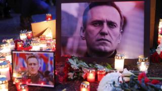 Candles and flowers sit next to the photo of Russian opposition politician Alexey Navalny