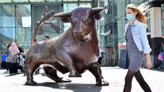 A shopper wearing a protective face mask walks past the Bull statue outside the Bullring shopping centre in Birmingham, central England on August 22, 2020.