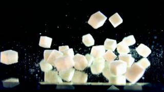 Sugar cubes falling against a black background