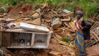 Umukecuru ahagaze impande y'inzu yiwe yasambuwe n'igihuhusi muri Mozambique, itariki 19/03/2019