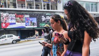 Cubanas usan su celular en La Habana.