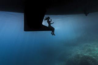 A silhouette of a woman surrounded by the blue background of the sea.