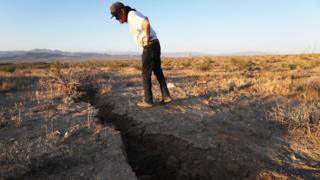 A local resident inspects a crack in the earth