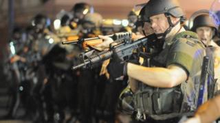 Armed law enforcement officers watch on during a protest on West Florissant Avenue in Ferguson, Missouri (16 August 2014)