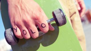 Скейтбордист со словом YOLO, написанным на их руке.