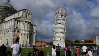Tourists pose for photographs at the Leaning Tower of Pisa