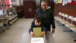 A woman cats vote with her son for the local elections in Ankara