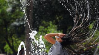 Eine Frau erfrischt sich im Wasser auf einem Platz in Córdoba, Spanien