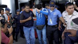 One of the Syrians is escorted by police at Tegucigalpa airport