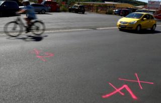 A car passes the marks left by police forensic experts on a street where shots were fired at a 26-year old Eritrean man in Waechtersbach, near Frankfurt, Germany, July 23, 2019