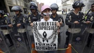 Женщина принимает участие в акции протеста перед штаб-квартирой CADIVI в Каракасе в феврале 2013 года. Около 500 работников газеты потребовали от правительства освободить доллары США для покупки бумаги, которой в настоящее время не хватает в Венесуэле