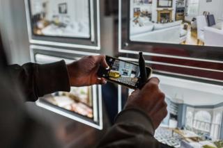 A person takes a photo of an advert in the window of an estate agent