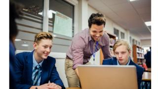 A teacher helps pupils at a school