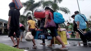 Orang-orang membawa barang-barang mereka berjalan menuju tempat perlindungan sementara di sekolah di kota Tabaco, Filipina. Foto: 24 Desember 2016